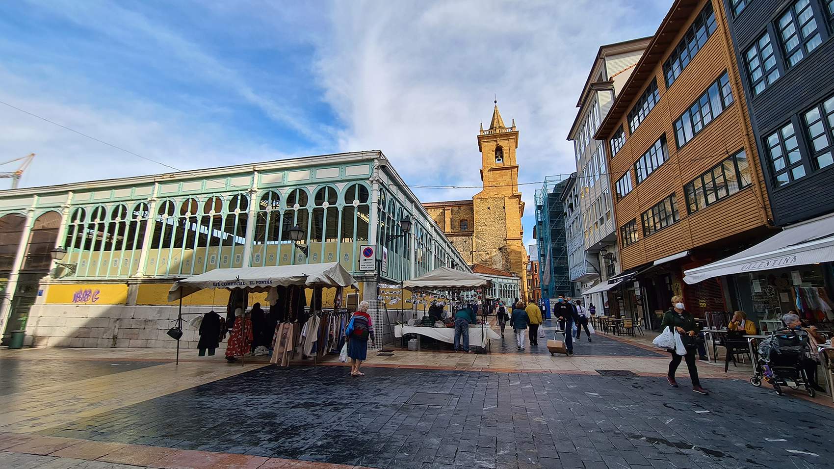 Foto de la plaza del Fontán, donde se pueden ver algunos puestos, la entrada al mercado, y de fondo la iglesia de San Isidoro el Real 