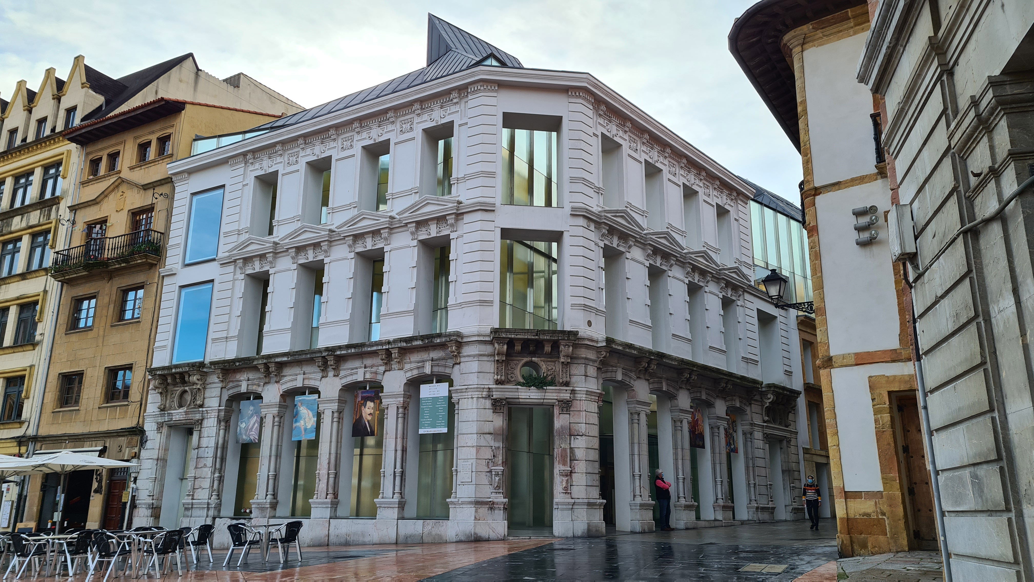 Fotografía de la entrada al museo de Bellas Artes de Oviedo, concretamente a la nueva ampliación donde se observa el edificio de fachada blanca articulada con ventanales y cristaleras que aportan gran luminosidad.