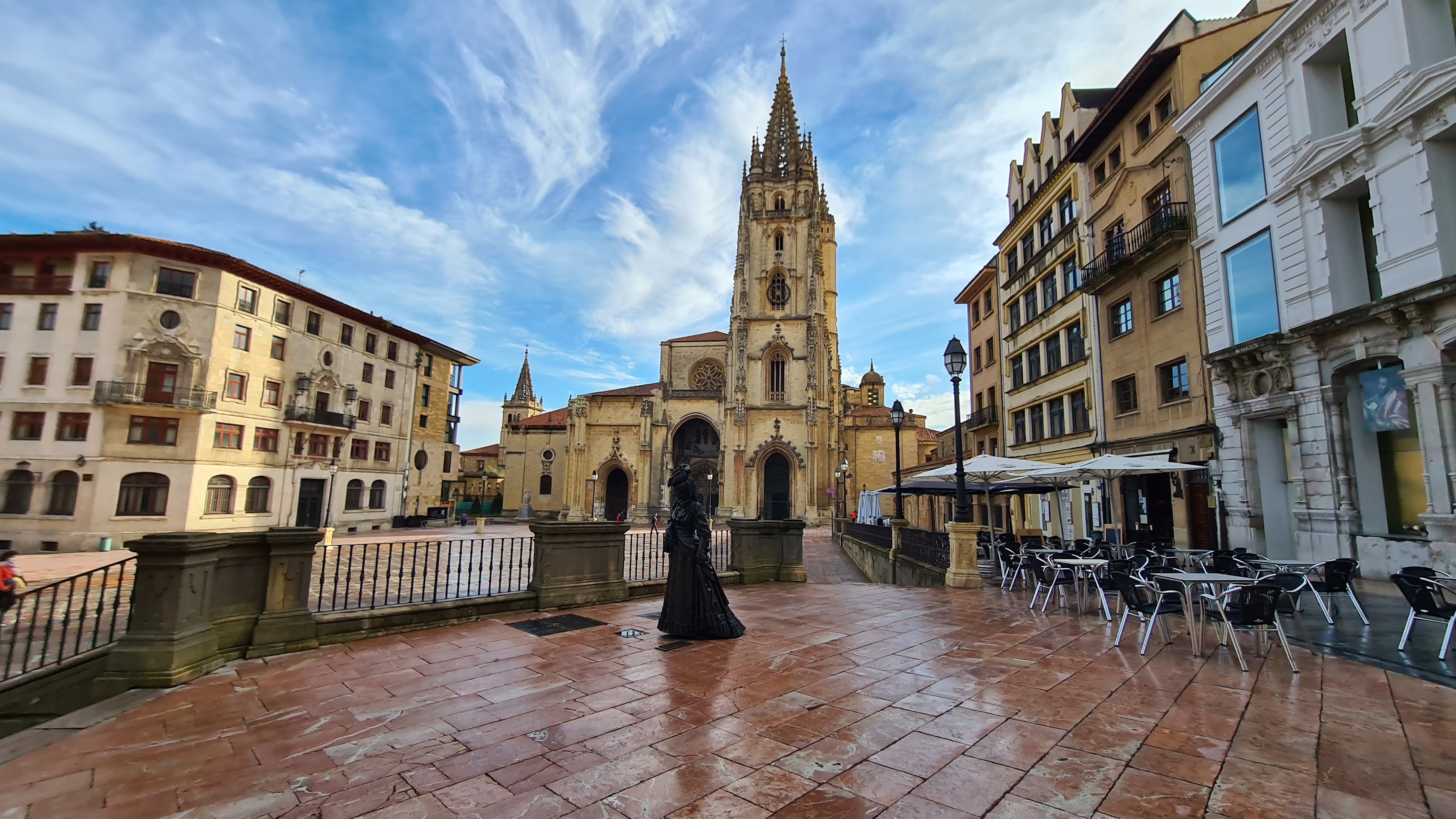 Foto panorámica desde lo alto de la plaza Alfonso II, en la que se ve en primer plano, la estatua de la Regenta, parte del museo de Bellas Artes, y de fondo la Catedral de Oviedo.