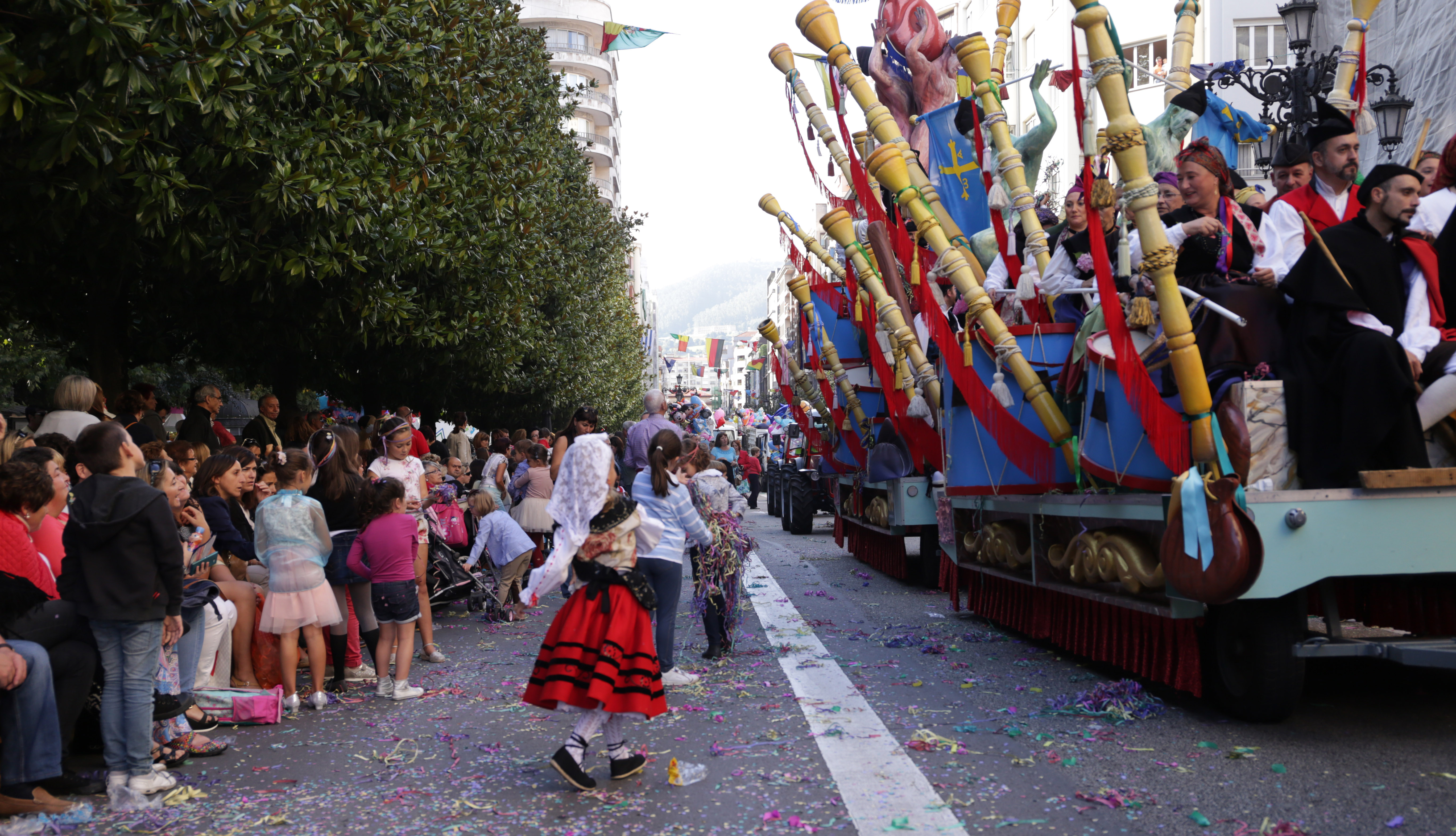 Fotorafía de las carrozas del desfile de San Mateo que discurre por la calle Uría donde podemos ver a niños y niñas jugando con las serpentinas.