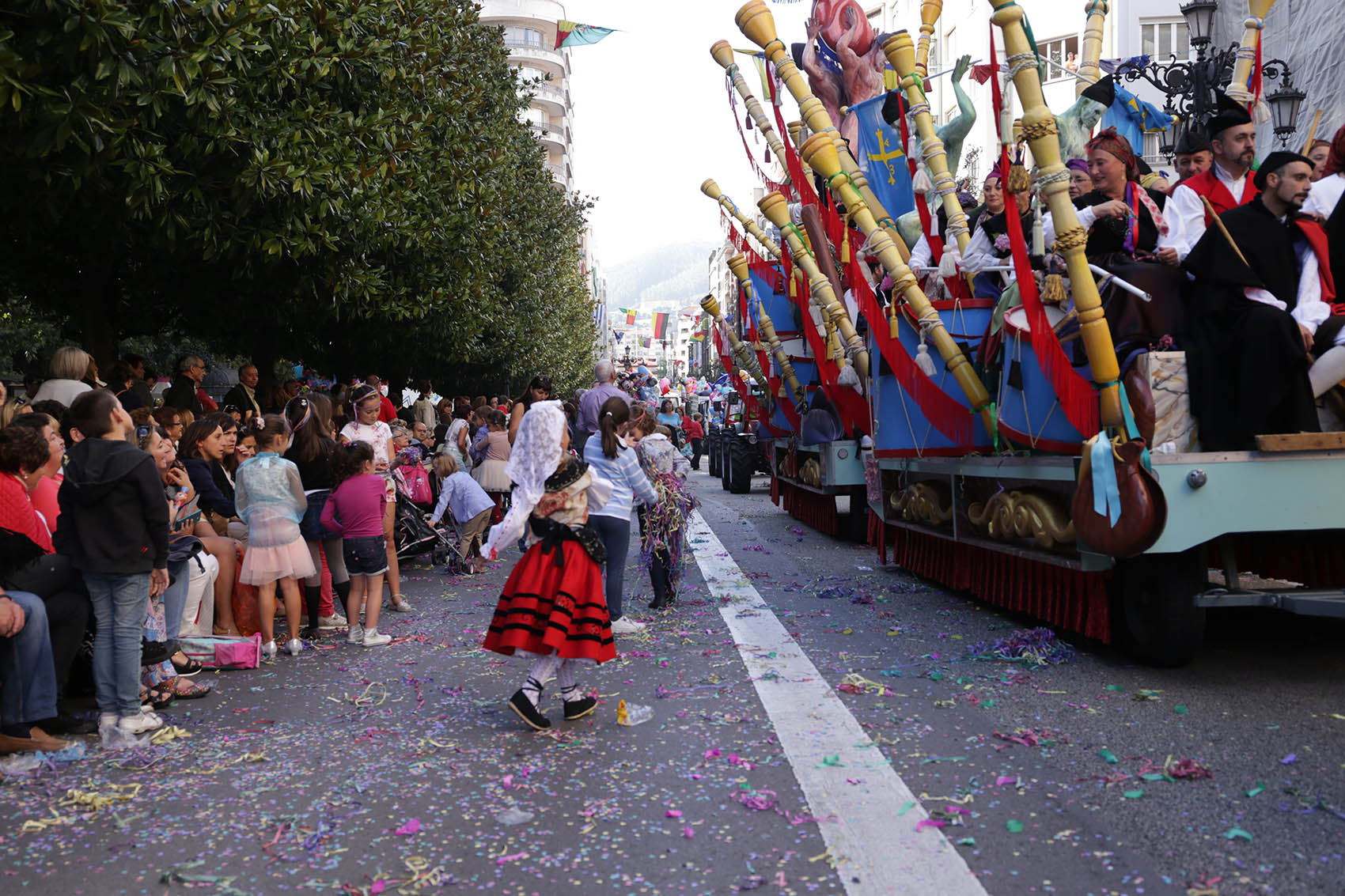 Fotorafía de las carrozas del desfile de San Mateo que discurre por la calle Uría donde podemos ver a niños y niñas jugando con las serpentinas.