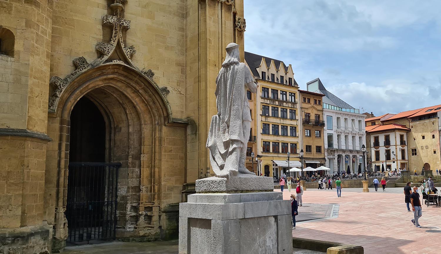 Panorámica del lateral de la Catedral de Oviedo, en la que también se puede ver la estatua de Alfonso II el Casto, así como la plaza que lleva su nombre, y los edificios circundantes.