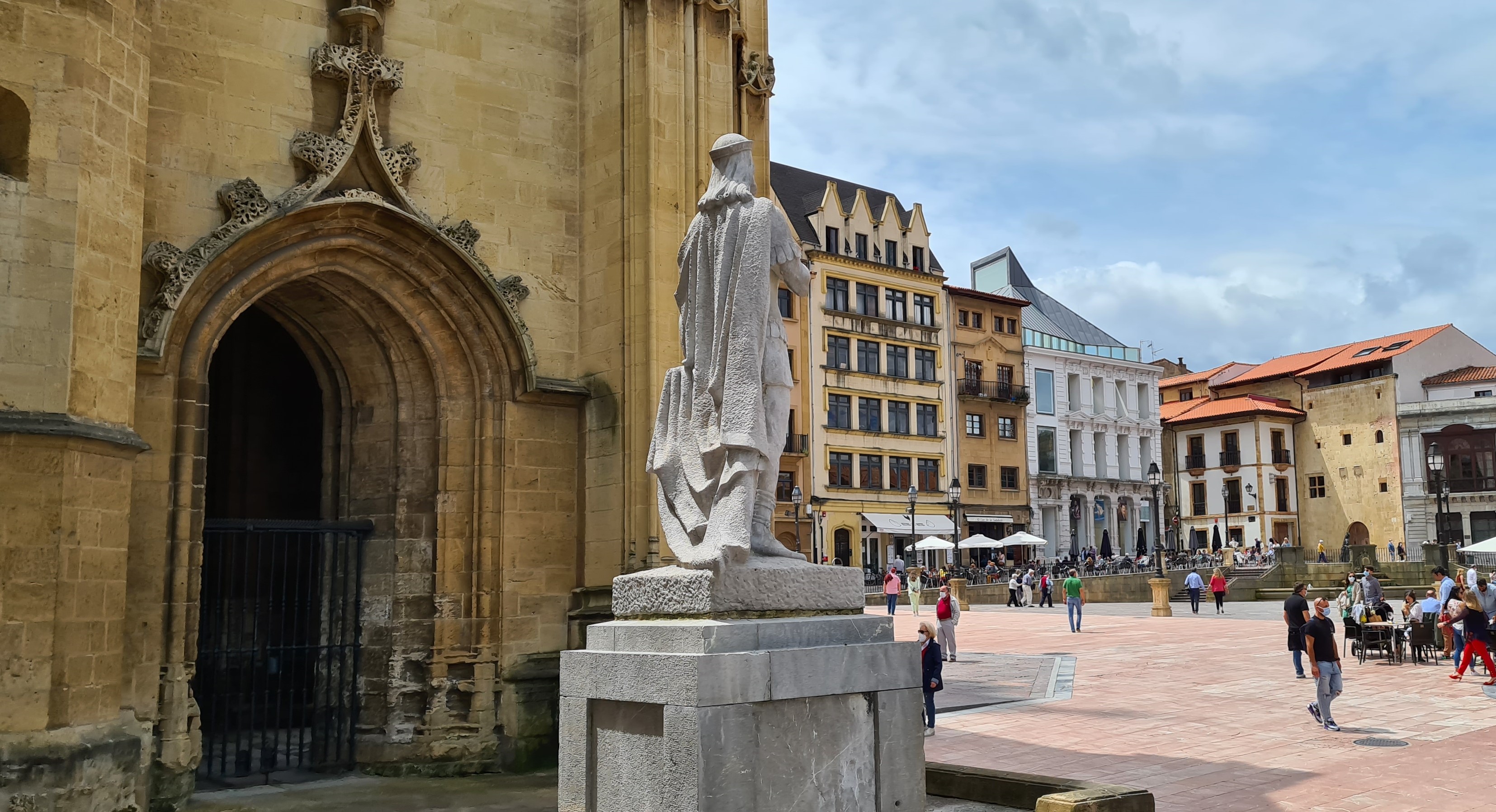 Panorámica del lateral de la Catedral de Oviedo, en la que también se puede ver la estatua de Alfonso II el Casto, así como la plaza que lleva su nombre, y los edificios circundantes.