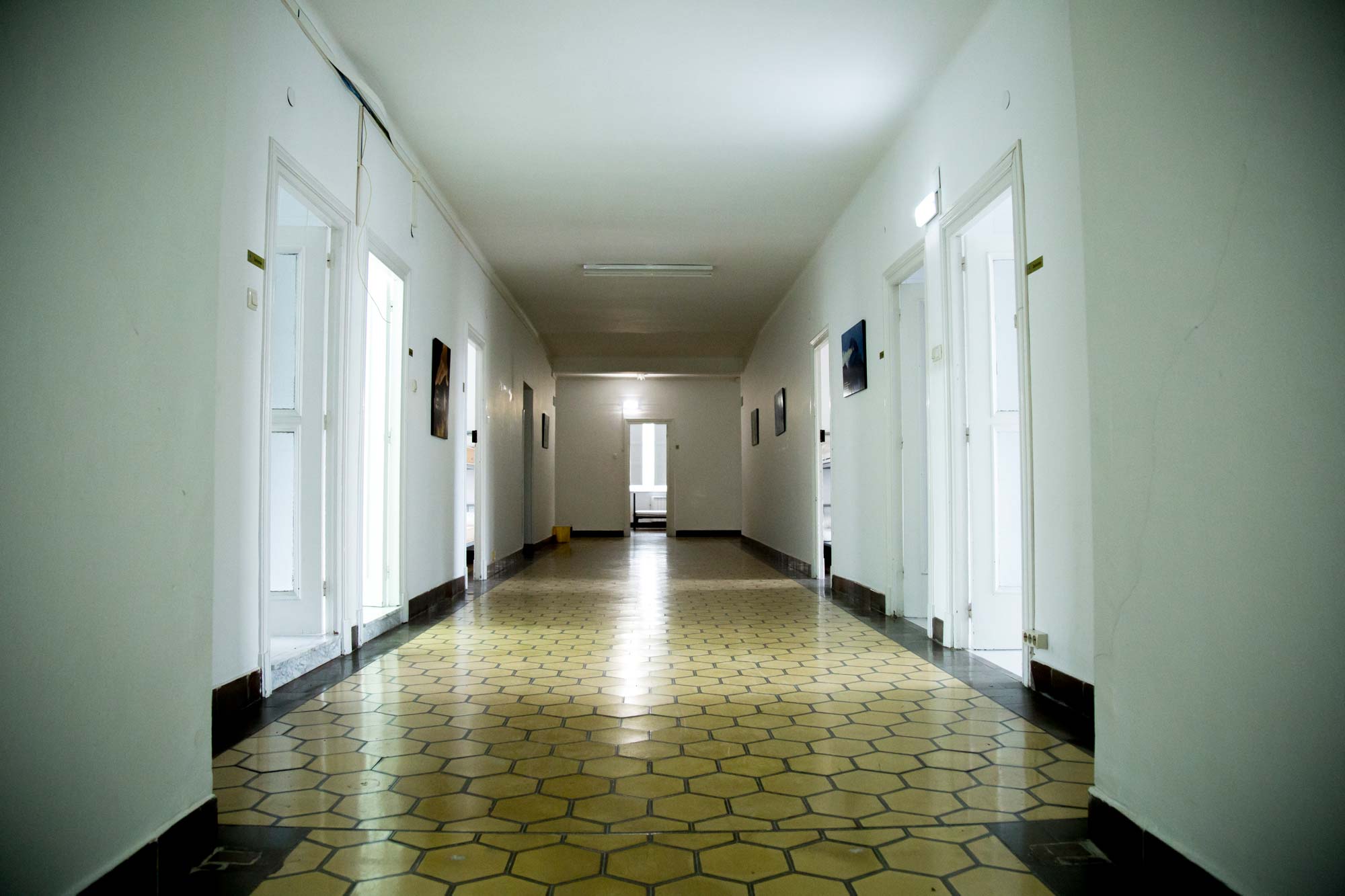 Fotografía del interior del albergue de El Salvador donse se ve en perspectiva el pasillo principal donde se sitúan las habitaciones con una gran luminosidad.