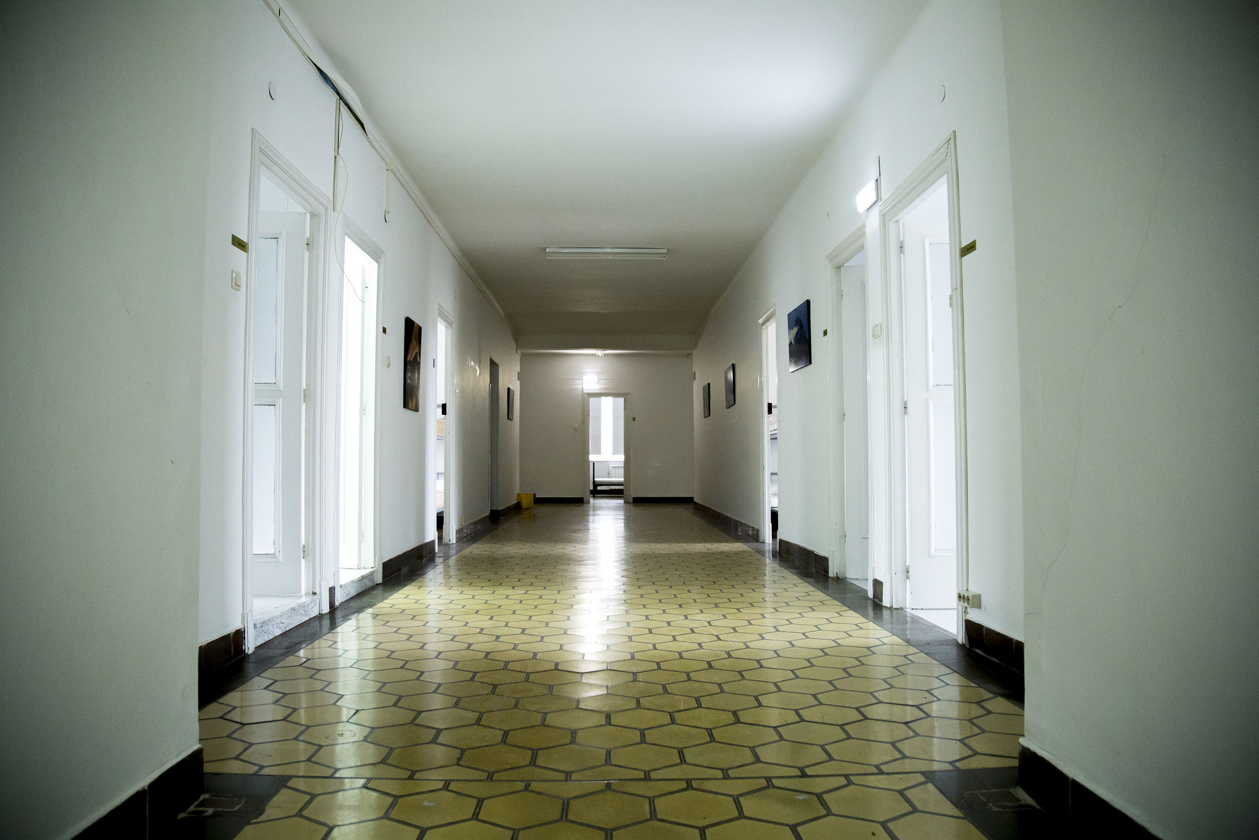 Fotografía del interior del albergue de El Salvador donse se ve en perspectiva el pasillo principal donde se sitúan las habitaciones con una gran luminosidad.